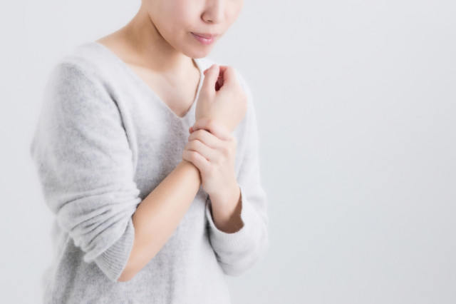 手首を抑える女性の写真