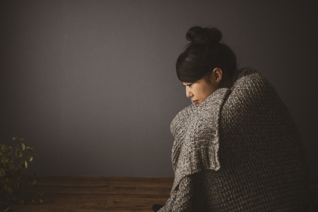 膝を抱える女性の写真
